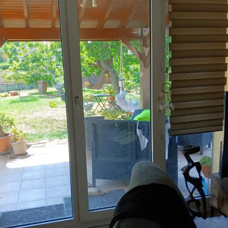 Ancienne porte-fenêtre blanche vue de l’intérieur, avec un store bateau, avant son remplacement